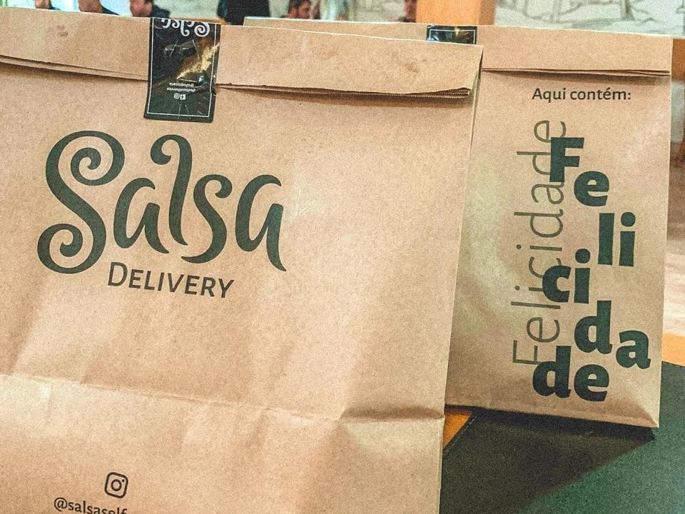 Sacolas kraft do Salsa Delivery com a frase 'Aqui contém: Felicidade'
